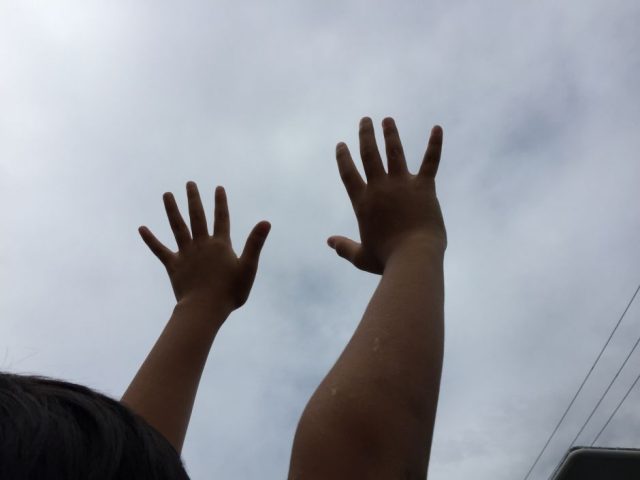 子どもが空に向かって手を伸ばす
